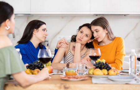 Female friends comforting upset woman at home gatheringの写真素材
