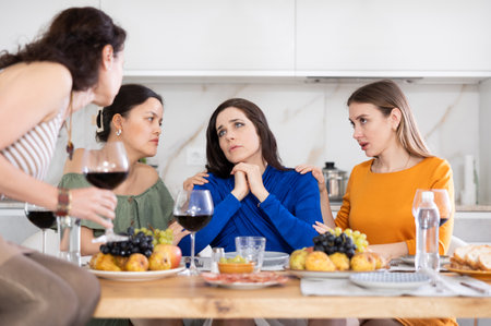 Female friends consoling upset bestie during friendly get-togetherの写真素材