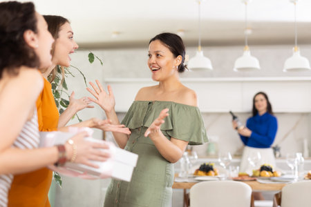 Two women have arrived for birthday celebration and presenting gift to birthday womanの写真素材