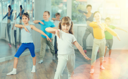 Children studying modern style dances with female teacher in dance class