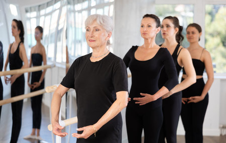 Group of women stand in position at ballet barre