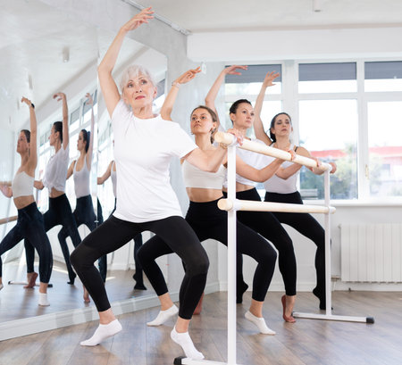 Girls in ballet class perform composition with grand plie with participation of mature female mentor