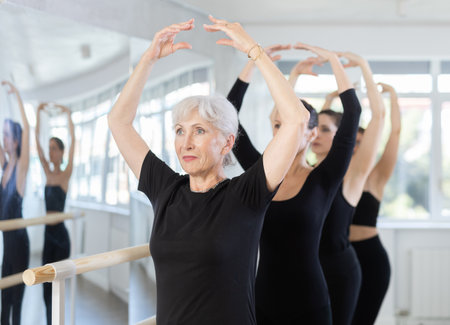 Girls in ballet class perform fifth position with participation of mature female mentorの写真素材