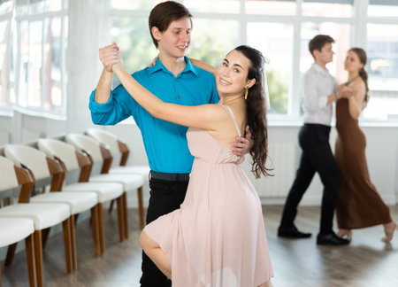 Young brunette practicing sensual bachata with guy in dance class