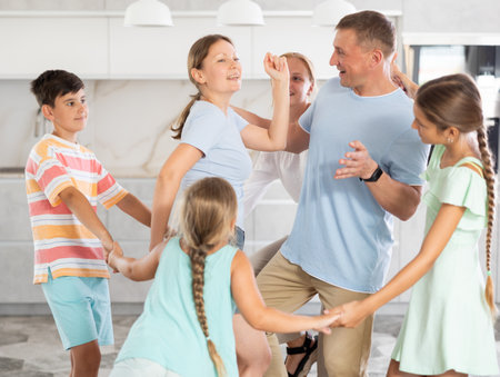 Happy cheerful parents together with children dancing in living room at homeの写真素材