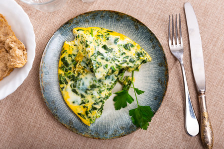 Omelet with spinach, decorated with sprig of parsley, slices of bran breadの写真素材