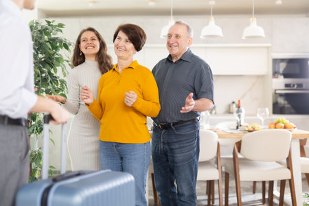 Senior parents and girl greeting young man at parental homeの写真素材