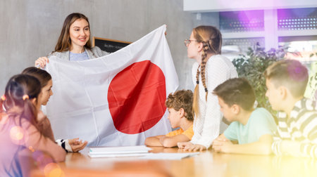 Female teacher shows scholchildren national flag of Japanの写真素材