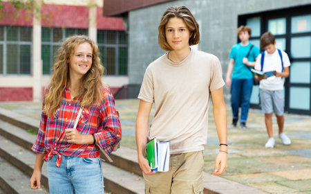 Positive teens walk along summer street after finishing college lessonsの写真素材