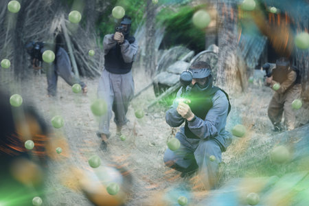 Team of positive smiling people playing paintball on battlefield outdoor, running with guns