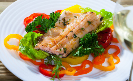 Tasty fried trout fillets, served at plate with vegetables and greens