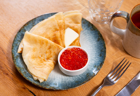 Service plate containing fried hotcakes with piece of butter and red caviar. Popular Russian dishの写真素材