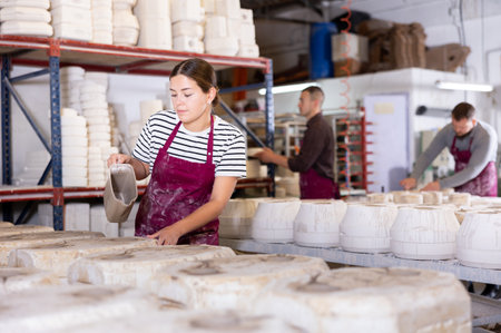 Female artisan pouring slip into casting molds in workshopの写真素材