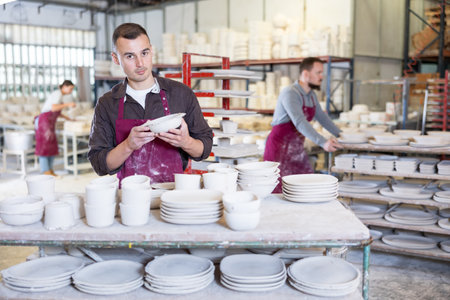 Pottery expert inspecting produced handmade plate in ceramics studioの写真素材