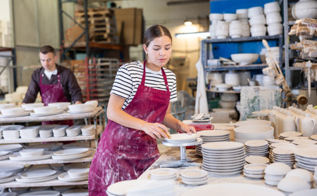 Young woman cleaning blanks of ceramic productsの写真素材