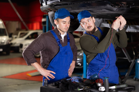 Two auto mechanics work together to diagnose an engine using a measuring device in car service centerの写真素材
