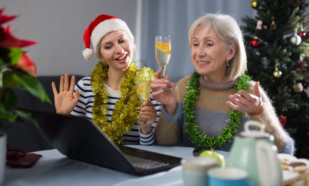 Mature woman and her adult daughter congratulate someone on Christmas via video linkの写真素材