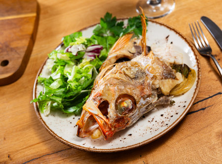 Roasted alfonsino fish head with crisp leafy salad