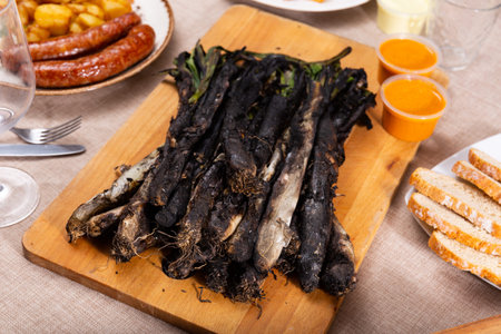 Traditional dishes of Catalonia, calcot with romesco sauce served on wooden board, bread and...