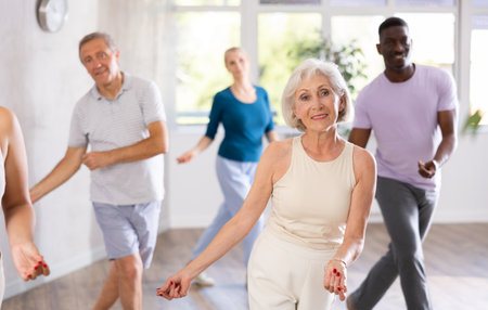 Mature men and women practicing Rock n Roll dance in training hallの写真素材