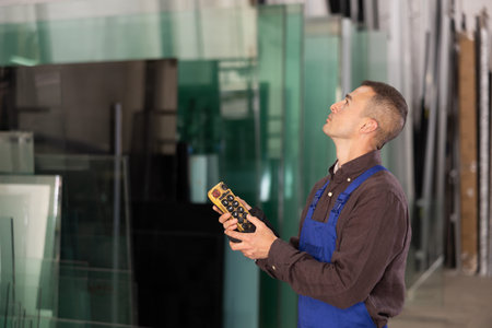 Male worker using control panel and lifting mechanism controls movement of window panes in an...
