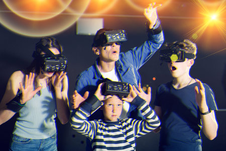 Family with children playfully poses in virtual reality glasses