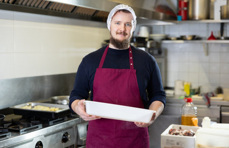 Male cook prepares chicken legs - cuts them with knife before cookingの写真素材