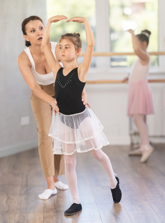Woman teacher corrects movement of girl dancer