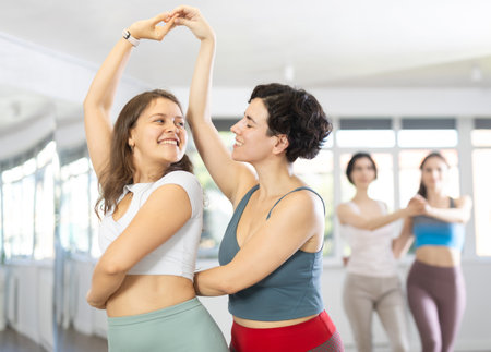 Two enthusiastic young women dancing salsa as dance partners in studioの写真素材