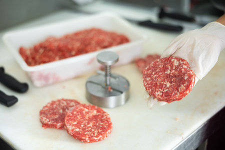 Raw beef burger patty in hand of butcher shop workerの写真素材