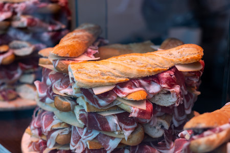 Stacks of bocadillos with jamon showcased behind shop windowの写真素材
