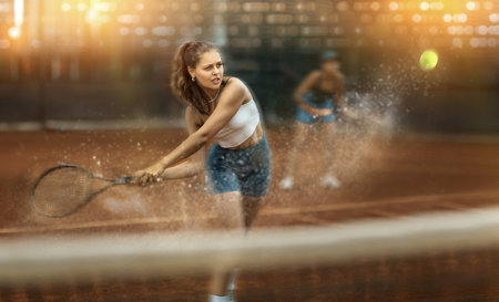 Stylized shot of young female tennis player swinging racket to hit ballの写真素材