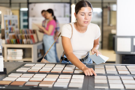 Young woman choosing tile samples in storeの写真素材