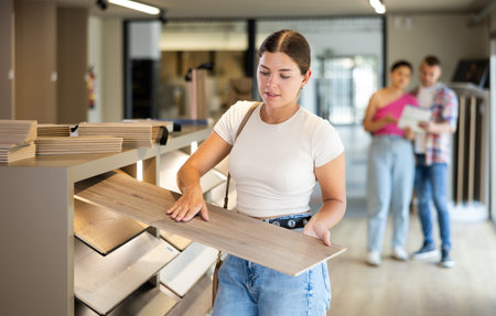 Young woman choosing laminate flooring in storeの写真素材