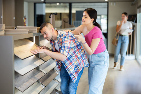Interracial couple discussing choice of laminate flooring in building hypermarketの写真素材