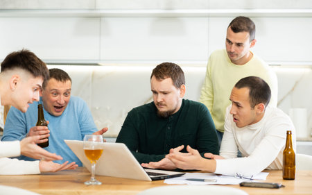 Men drink beer and try to help friend solve problems using laptop and Internet