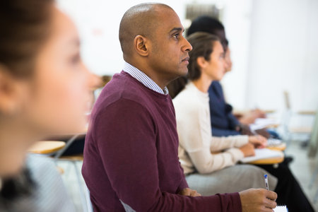 Multiethnic group of adult people studying together at tables . Focus on Latin American manの写真素材