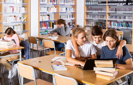 Teenage students working in groups in libraryの写真素材