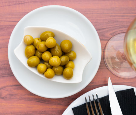 Pickled green olives served with glass of wineの写真素材