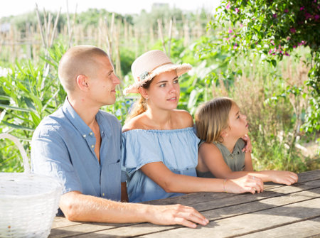 Portrait of happy family at table in courtyard of country house