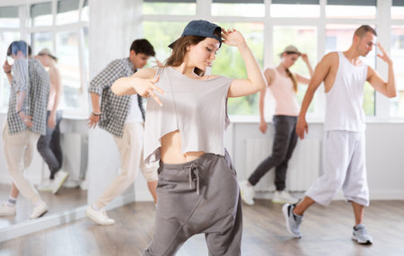 Young girl standing performs basic hip hop movements in front of group of students