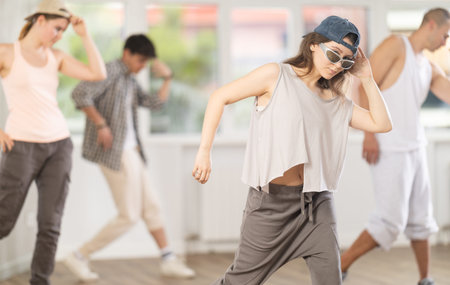 Young girl standing performs basic hip hop movements in front of group of students
