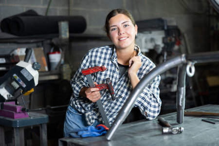 Female worker with clamp posing in metalworking shopの写真素材