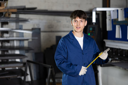 Guy posing with tape measure in metallurgical workshop
