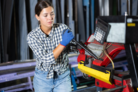 Female worker operating metal profile cutting machine in workshopの写真素材