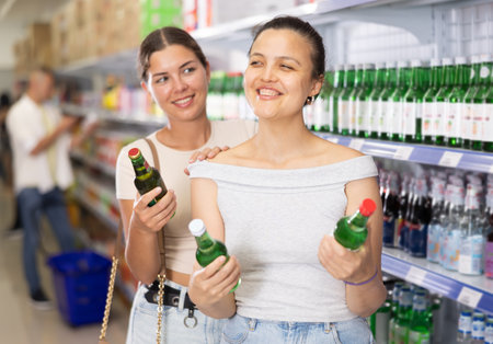 Young women discussing choice of alcoholic drinks in supermarketの写真素材