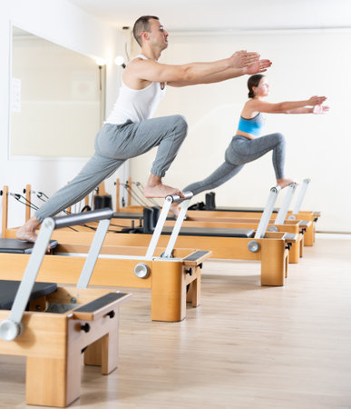 Focused man practicing exercises on Pilates reformer in studioの写真素材