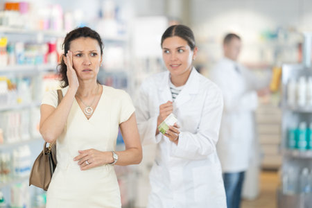 Female pharmacist advises medicine for head pain to womanの写真素材