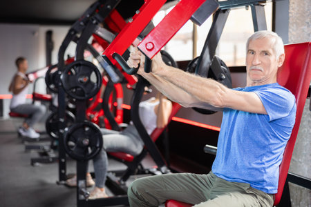 Elderly man trains his arms on machine