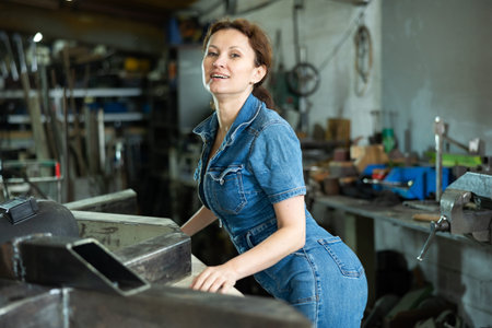 Woman employee of carpentry workshop took time out from work, stands resting